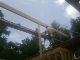 Carpenter setting a ridge beam over a new addition frame — Ice Dam Removal by Roofing Brothers in Broussard