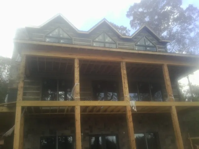 Dormers and porch framing on a large log home under construction — Roof Coating work by our crew in Broussard