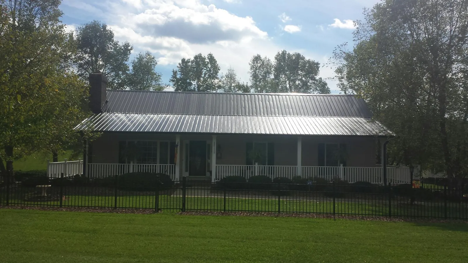 Gray metal roof on a brick ranch with a full width front porch — Gutter Guard Installation work by our crew in Broussard