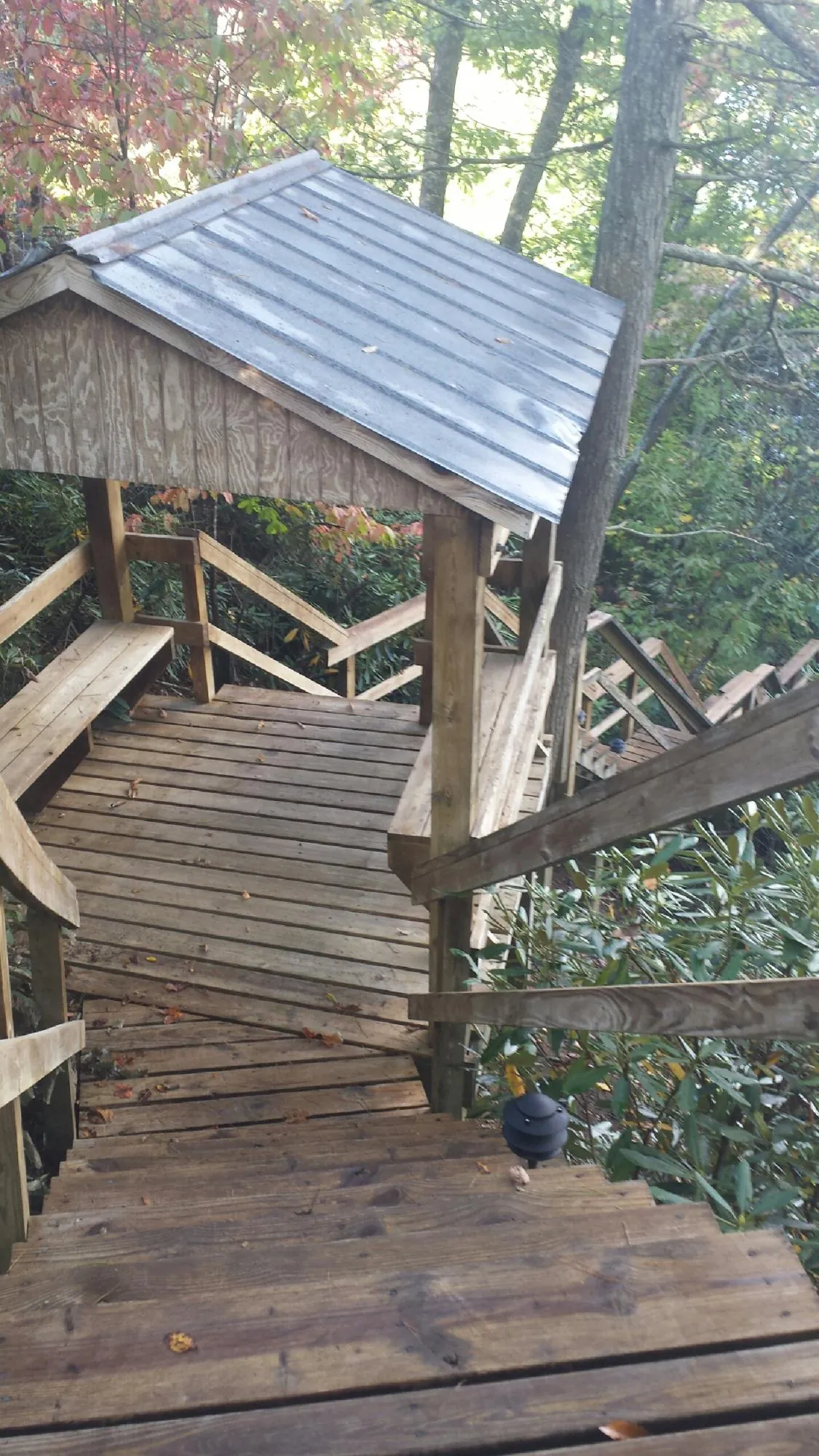 Metal roofed shelter over wooden steps on a wooded walkway — Skylight Repair & Installation work by our crew in Broussard