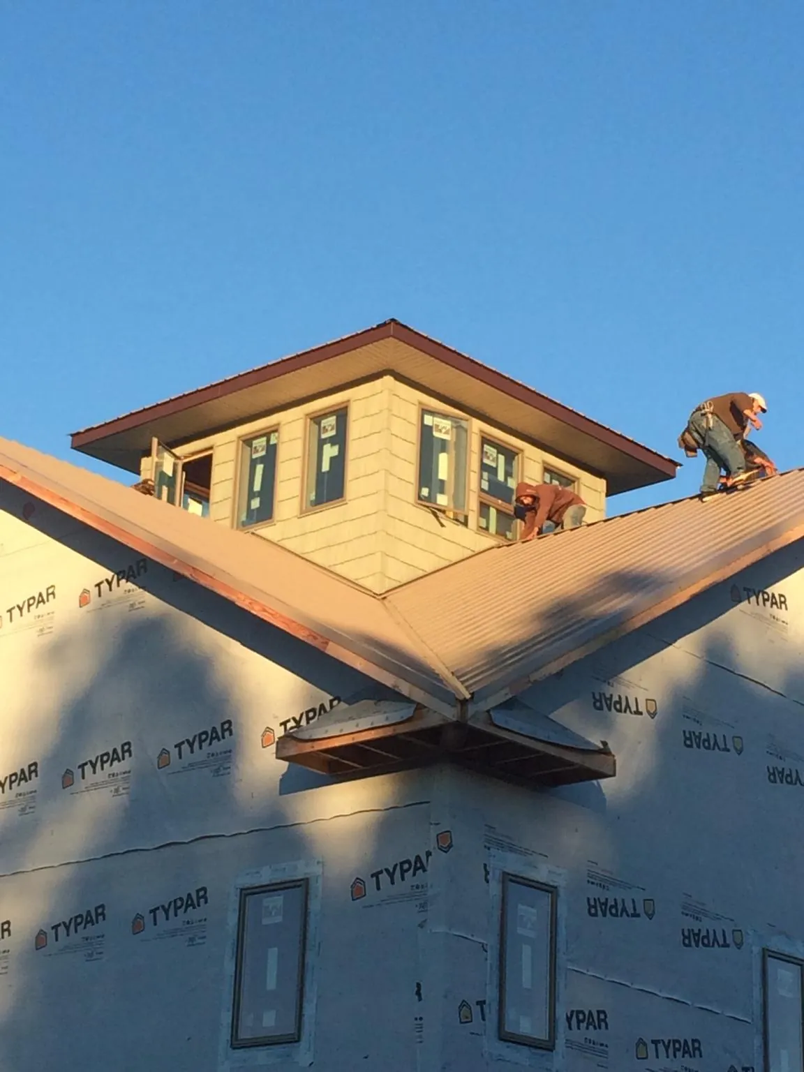 Roofers working around a rooftop cupola on a new metal roof at sunset — Roof Waterproofing in Broussard by Roofing Brothers